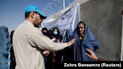 BMG-niň Bosgunlar edarasynyň işçisi öýlerinden göçürilen aýallara Kabulyň eteginde ýardam kabul etmegiň düzgünlerini düşündirýär. Arhiw suraty.