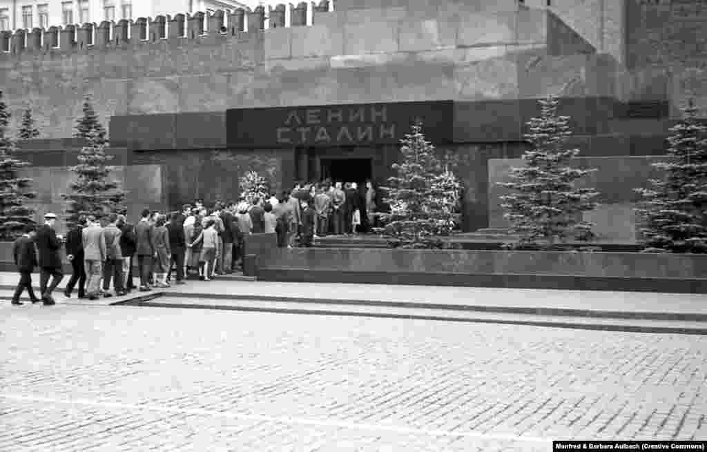 Посетители заходят в мавзолей Ленина и Сталина, август 1957 года. После смерти Иосифа Сталина в 1953 году его тело забальзамировали и разместили рядом с трупом Ленина. Над входом в мавзолей появилась вывеска с фамилиями двух советских диктаторов 