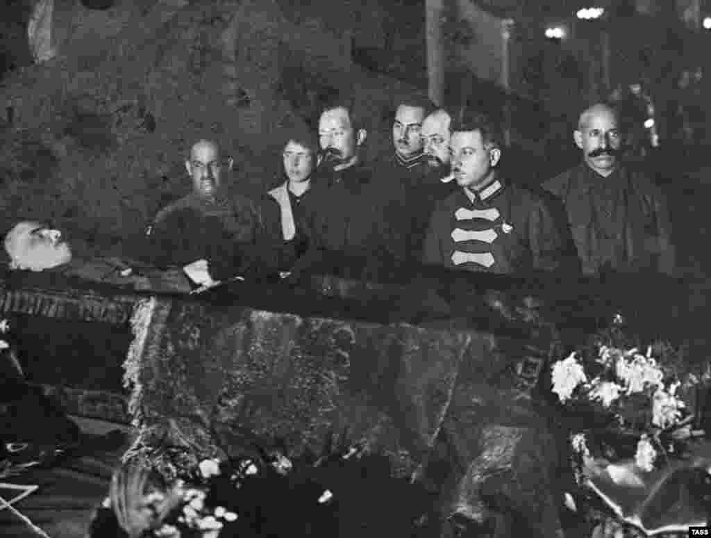 Большевистские начальники, в том числе Феликс Дзержинский (третий слева), печально известный основатель советской тайной полиции, организовавший множество массовых убийств, смотрят на тело Ленина. Конец января 1924 года. После смерти Ленина разгорелись дискуссии о том, что делать с его телом. Иосиф Сталин настаивал на том, чтобы труп забальзамировали и выставили на всеобщее обозрение, заявив, что это «не будет противоречить старым русским обычаям». Лев Троцкий, ещё один лидер большевиков, отверг идею сделать из тела революционера-безбожника реликвию. Сохранение трупа для публичного поклонения не имеет «ничего общего с марксизмом», возражал он
