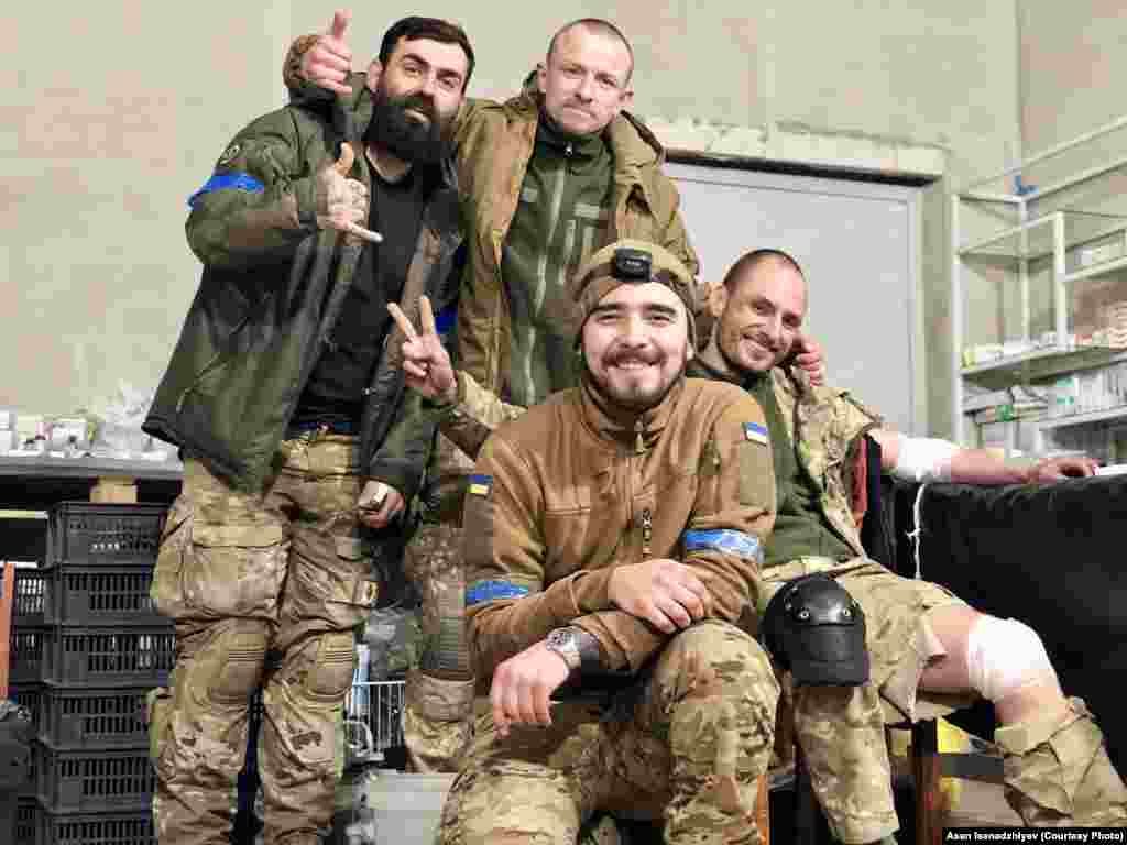 Маріуполь, 2022 рік. В центрі на цьому знімку – бойовий медик Асан Ісенаджиєв, який надав Радіо Свобода ці фотографії. Він вийшов з «Азовсталі» у травні 2022 року з останніми українськими підрозділами, що залишалися на оточеному заводі. Разом з іншими бійцями він був ув’язнений в колонії в Оленівці і вижив після підриву бараку з полоненими. 31 грудня 2022 року Асана обміняли. З ним на цій світлині позують бійці «Вишня», «Шпрот» та «Грян» (зліва направо). Вони прорвалися в оточений Маріуполь на гвинтокрилах. Із них трьох в живих залишився лише «Вишня» – він також пройшов російський полон, а після обміну повернувся у військо. «Шпрот» та «Грян» загинули в Маріуполі навесні 2022 року