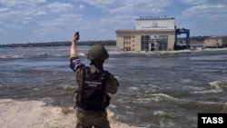 Представник окупаційних військ Росії на лівому березі Дніпра стоїть навпроти знищеної Каховської ГЕС, Україна, червень 2023 року