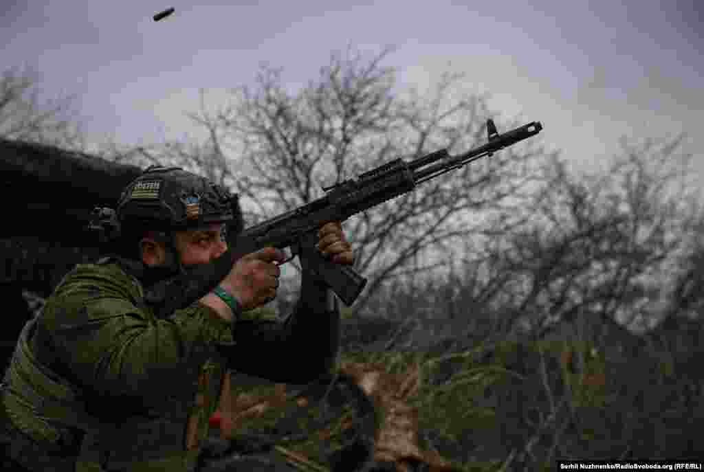 Украинский военнослужащий из 93-й механизированной бригады стреляет из автомата АК-74 по российским позициям возле Бахмута 6 марта. Несмотря на нехватку артиллерии и техники, украинские войска пытаются замедлить продвижение российских войск на фронте протяжённостью почти 1200 километров 