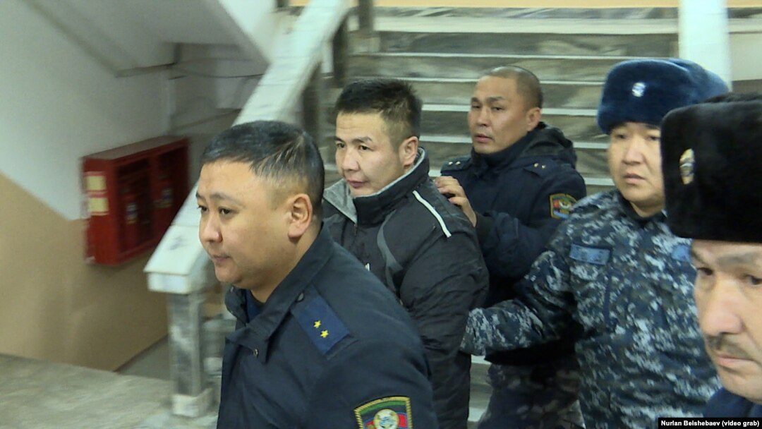 Azamat Estebesov (center) is escorted by police in January.