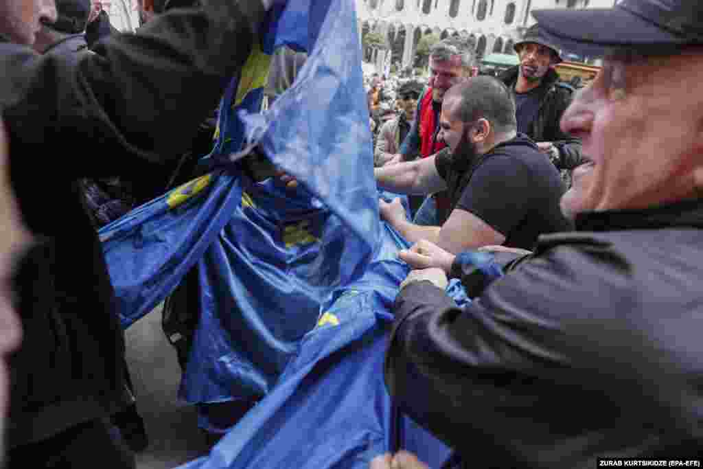 Susținători ai Mișcării Conservatoare și ai platformei pro-ruse Alt-Info rup un steag al UE, în timpul unui miting în fața clădirii parlamentului din Tbilisi, 14 martie.