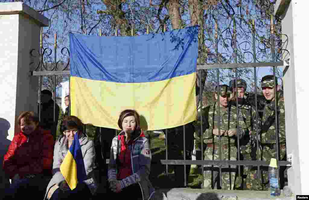 У селищі Любимівка українські військовослужбовці збираються на території військової частини. Їхні родичі сидять біля паркану, щоб не допустити збройних зіткнень, 3 березня 2014 року 