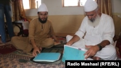 Kleriku Mian Mohammad Javed (djathtas) dhe djali i tij, Mian Noor Muhammad, me ditarin e të konvertuarve në Islam.