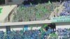 20 müň tomaşaçy üçin niýetlenen “Aşgabat” stadionynyň tribunalaryny dolduryp oturan studentler we edara işgärleri ýörite "režissýoryň" görkezmesi boýunça hereket edýärler. Aşgabat, 20-nji sentýabr, 2012.