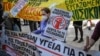 Жена држи плакат „Масовни вработувања, пари за болници“ за време на демонстрациите во Атина, 22.04.2021.