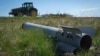 A fragment of a Russian missile lies in a field as a farmer works his land in Ukraine's war-torn Kharkiv region. 