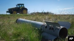 Dio ruske rakete na zemlji dok poljoprivrednik obrađuje svoje polje u ratom razorenoj Harkivskoj oblasti, Ukrajina, april 2024.
