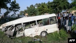 Residents gather around the wreckage of a van alongside a railway track following the fatal accident in Punjab Province on July 3.