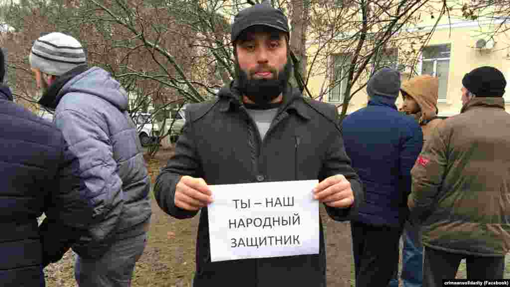 Люди, які прийшли підтримати адвоката, фотографуються з плакатом «Ти – наш народний захисник»