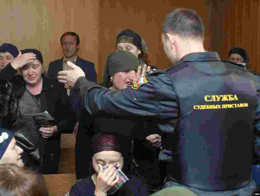 Sud işgäri Beslandaky zamun alyşa gatnaşan we ele salnan ýeke-täk söweşiji Nurpaşi Kulaýewiň sud edilen wagtynda gepleýän zenany köşeşdirmäge synanyşýar, Wladikawkaz, 19-njy maý, 2005.