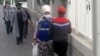 Aşgabadyň köçesinden barýan ýüzi maskaly adamlar.