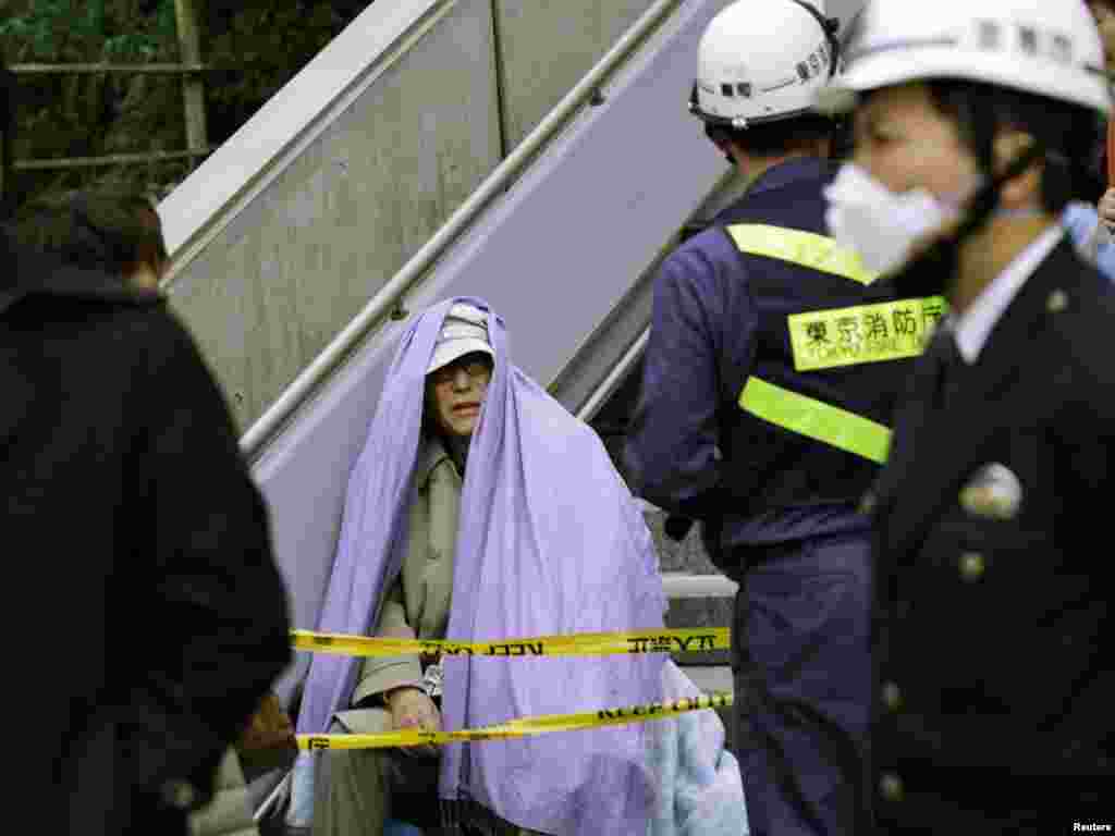 Japan - A man sits wrapped in a blanket after he was evacuated from a building in Tokyo's financial district, after an earthquake off the coast of northern Japan, 11Mar2011 - Человек сидит, завернутый в одеяло, после того, как он был эвакуирован из здания в финансовом районе Токио. REUTERS / Kim Kyung-Hoon 