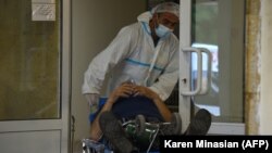 Armenia -- A medical worker wearing protective equipment moves a patient into the Grigor Lusavorich Medical Center in Yerevan, June 9, 2020