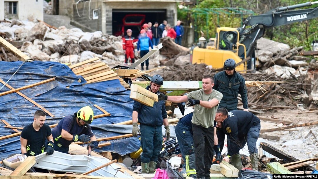 Rescue workers and locals in the village of Glogosnica begin cleaning up on October 5, a day after deadly floods and landslides in southern Bosnia. 