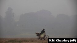 A cyclist pushes his laden bike through smog, in Lahore on November 21