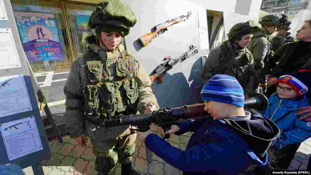 23 лютого, Сімферополь. Люди в російській військовій формі показують дітям зброю та дають її їм у руки. Правозахисники вказують на те, що мілітаризація освіти і дитинства, пропаганда війни серед дітей – це порушення Конвенції про права дитини, яка зобов'язує виховувати дітей у повазі до норм міжнародного гуманітарного права