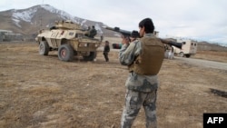 An Afghan security officer holding a rocket-propelled grenade stands at the sire of a deadly attack on an army base in Ghazni Povince on November 29.