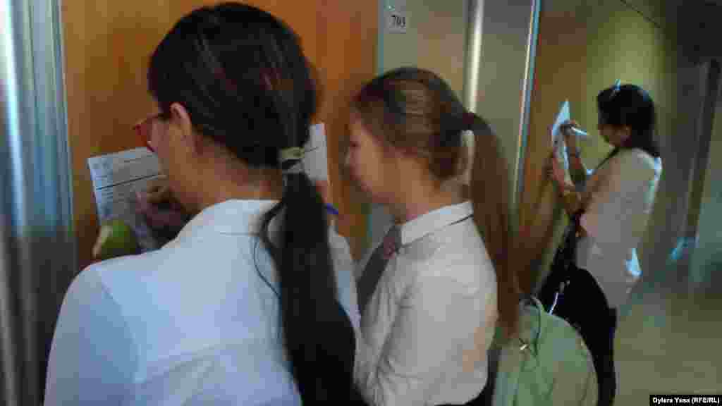Девушки записывают нужные для себя сведения на выставке «Международное образование».