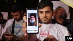 Bir adamyň telefonunyň ýüzünde Hezbollah toparynyň baş sekretary Hassan Nashrallahyň suraty
