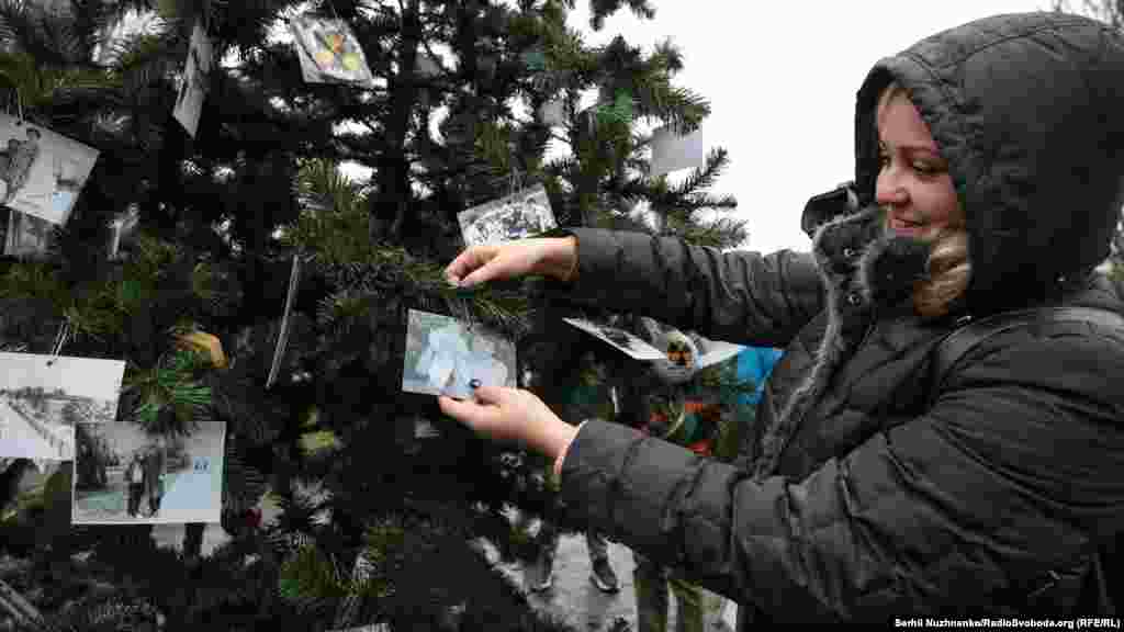 Дарина Дударенко прикріплює сімейне фото на встановленій новорічній ялинці. Вона народилася в Прип'яті в січні 1986 року