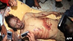 Люди фотографируют тело мертвого Муаммара Каддафи. Мистрат, 20 октября 2011 года. 