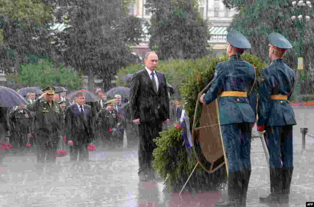 Германиялық нацистердің Совет Одағына басып кіруіне 76 жыл толуына орай Мәскеуде өткен қаралы жиын кезінде Ресей президенті Владимир Путин Белгісіз солдат қабірі алдында қалың нөсердің астында тұр. 22 маусым 2017 жыл. Алексей Дружинин 22 маусым күні таңертең Мәскеуде күн салқын әрі ауа райы құбылмалы болды деп еске алады. Фотограф "Мәңгілік алау" басына жеткенде аспан шайдай ашылған. Бірақ президент бастаған делегация гүлдестеге жақындаған сәтте жаңбыр шелектеп құйып кеткен. Автор Азаттықтың Орыс қызметіне Мессенджер арқылы жұрттың әлгі фотосуреттегі қолшатырсыз Путинді қызу талқылағанын айтқан. Кейінірек Путиннен "Қолшатырдан неге бас тарттыңыз?" деп сұрағанда, әрдайым өзін "мықты адам" етіп көрсететін ол: "Еріп кететін қант емеспін ғой" деп жауап берген.
