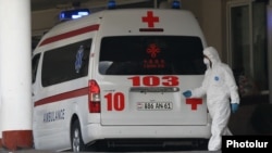 Armenia -- A medical worker clad in protecive gear and an ambulance parked at the entrance to Surp Grigor Lusavorich hospital, Yerevan, April 8, 2020.